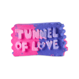 Tunnel of Love. A rectangular, ticket stub-shaped bath bomb with serrated edges. The product is half pink and half purple with raised lettings which reads "Tunnel of Love" on the front with the "O" in love as a heart. 
