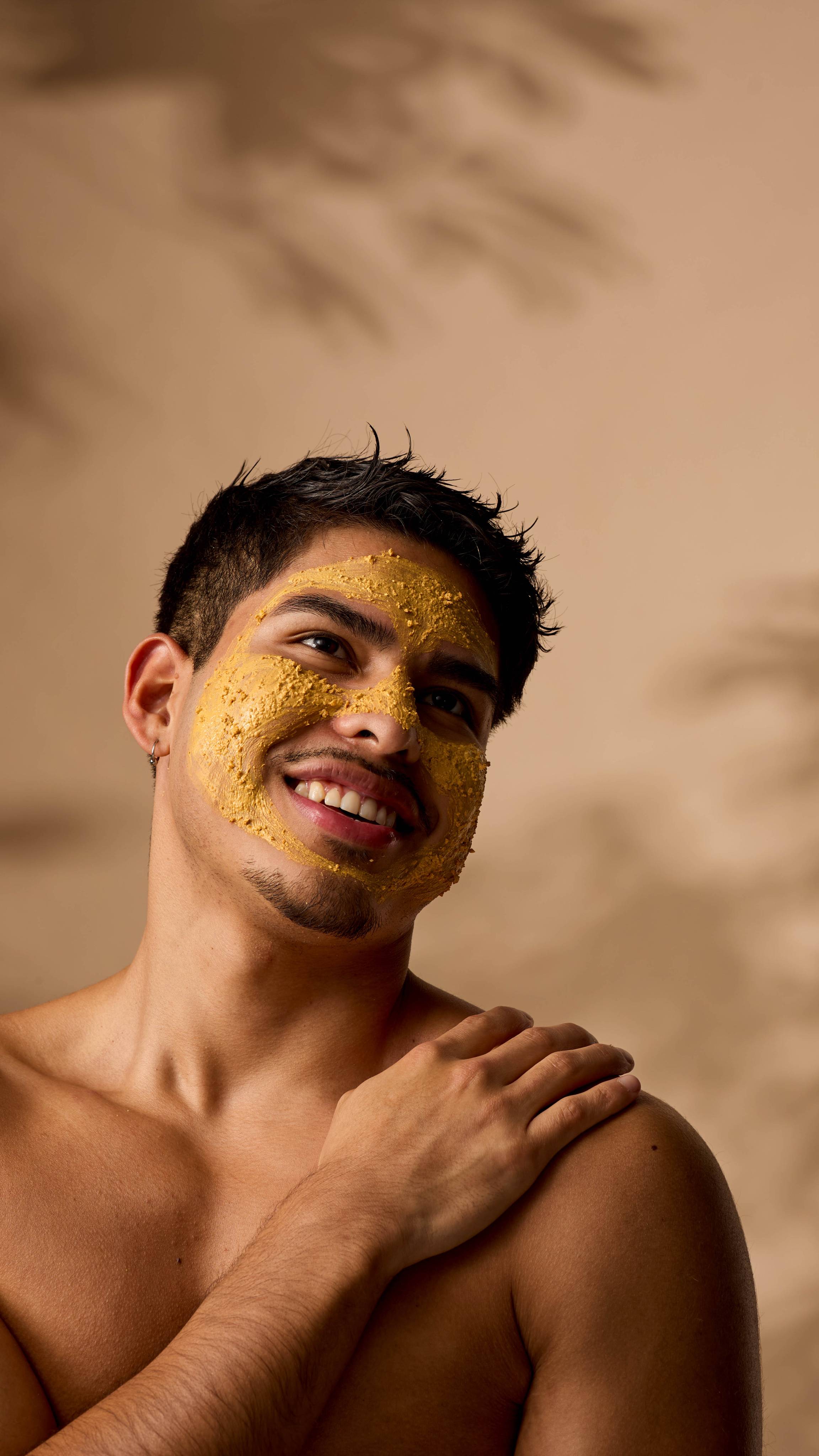 The image shows the model smiling into the distance as their skin is coated with the Turmeric face mask.