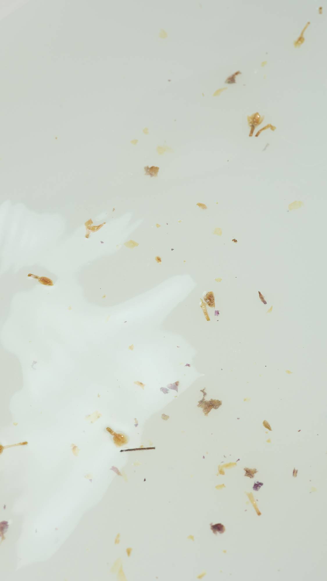 A super close-up aerial image of the bath water after using the Lush Two Hearts bath salts packet. There are tiny flecks of ingredients in the water. 