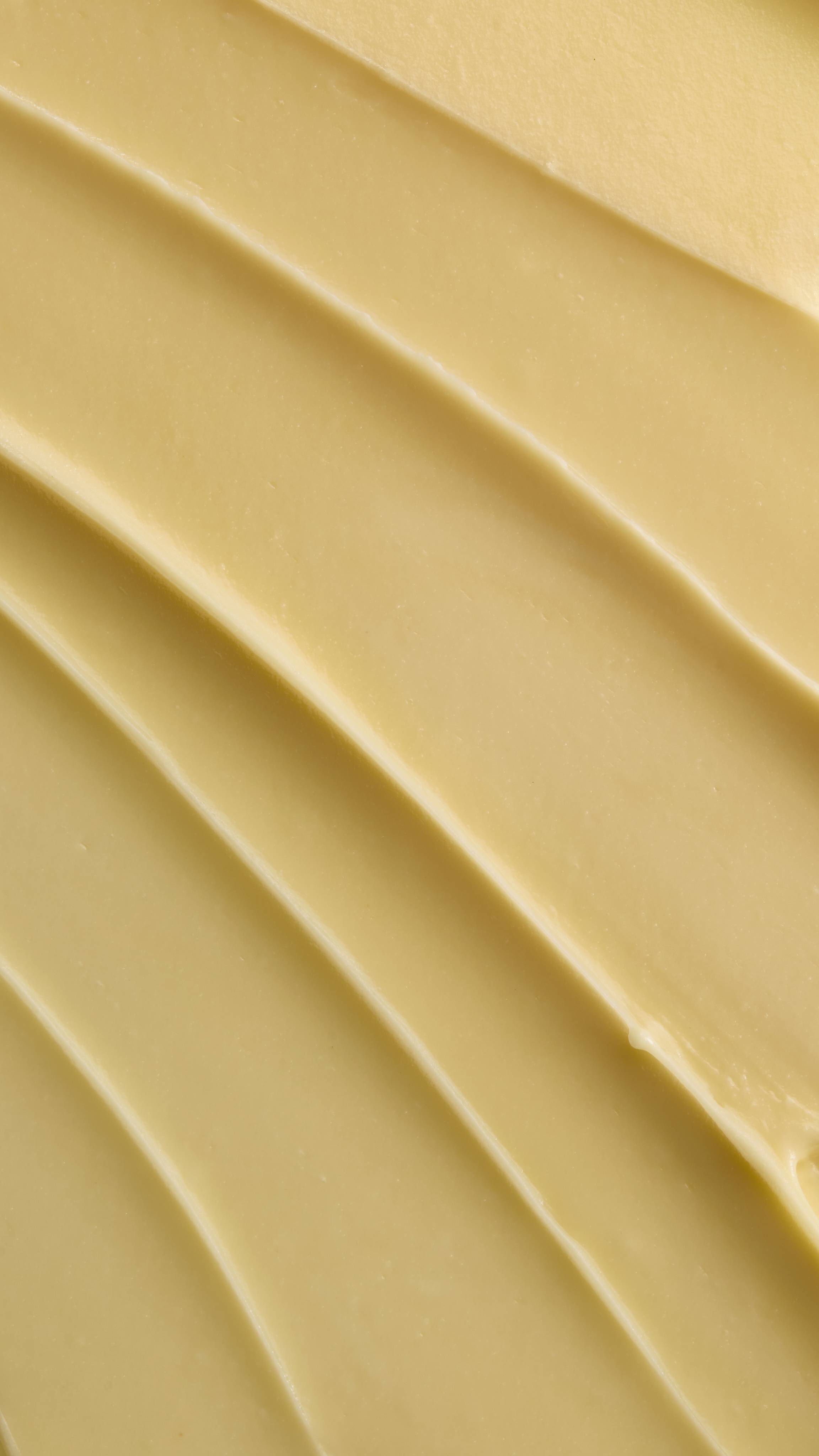A close-up texture shot of pale yellow Ultrabland cleanser spread out in thick, smooth ridges, highlighting its rich and creamy consistency.