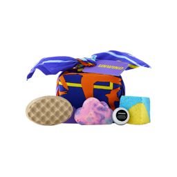 A knot-wrapped "UNWIND" gift set in blue and orange fabric, alongside a waffle-patterned massage bar, a pastel cloud bubble bar, a small tin, and a blue and yellow bath bomb block.