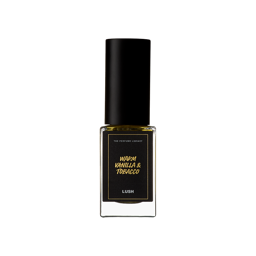 A rectangular glass bottle of Warm Vanilla & Tobacco perfume by Lush. It features a tall black cap and a black label with gold text, containing a yellowish-amber liquid.