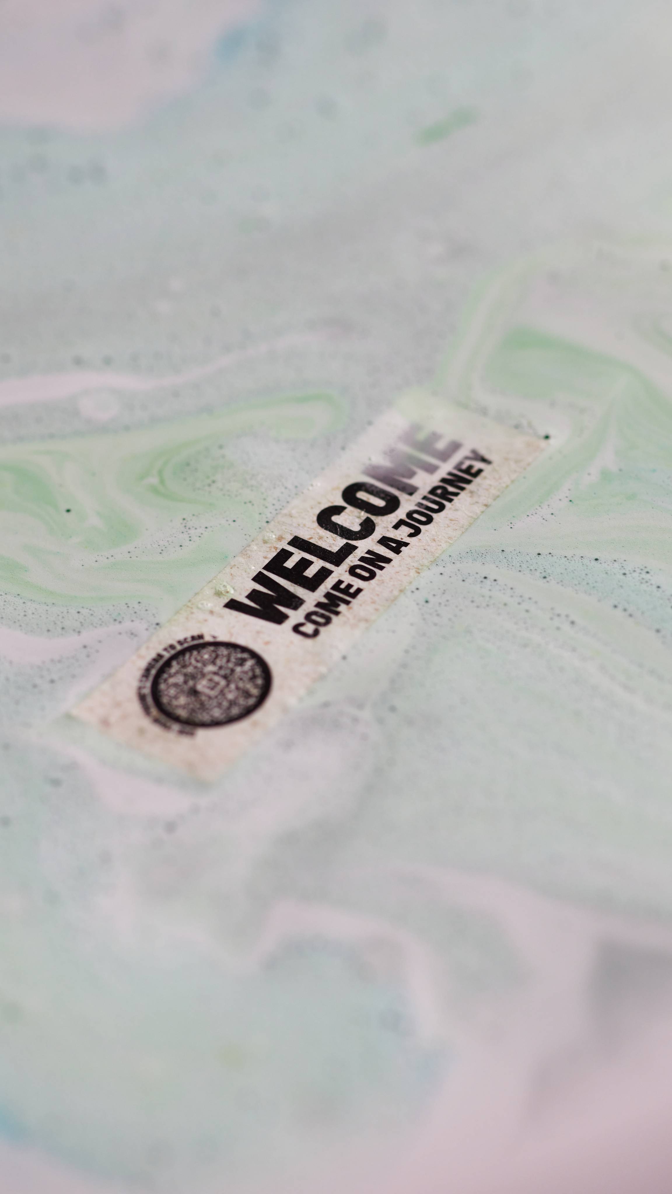 Welcome bath bomb melts leaving a small rice paper note with "Welcome - come on a journey" printed with a scannable QR code.
