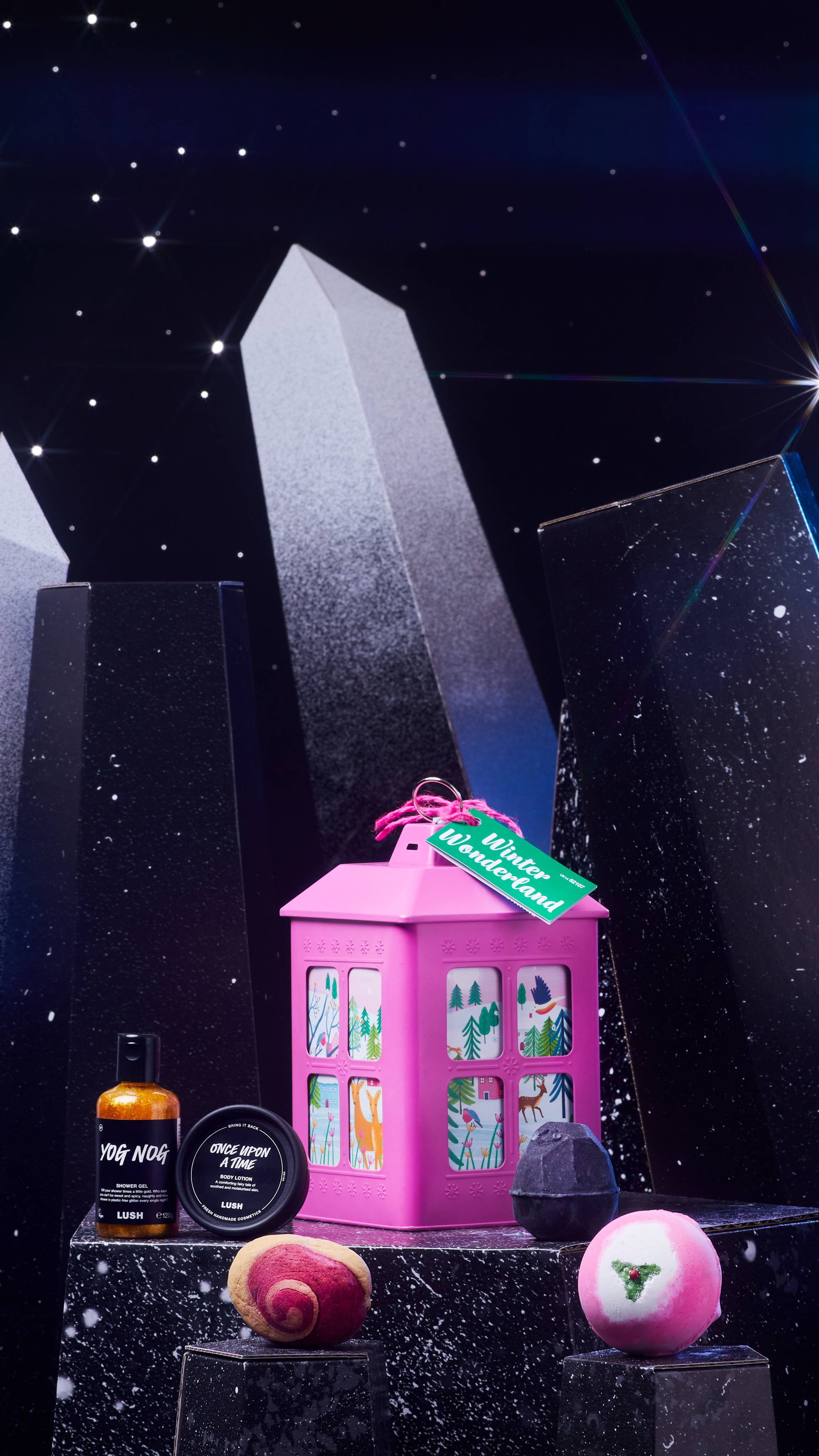 Winter Wonderland pink tin with the five included products are on a dark chromatic platform among geometric shapes. 
