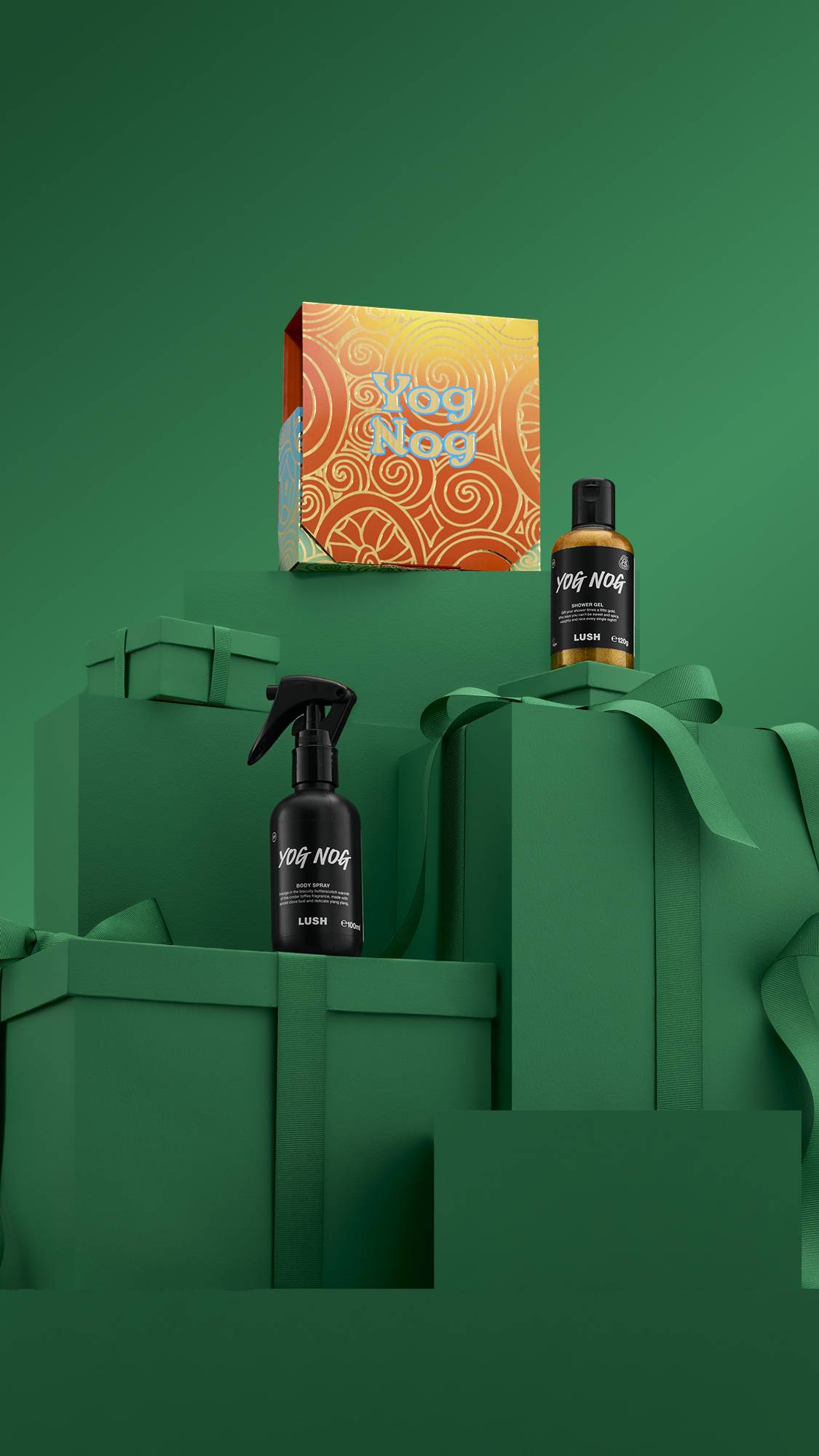 The image shows a large pile of differently-sized wrapped green gifts with ribbons, on a matching green background. The vibrant golden Yog Nog gift box sits on top of the pile, and the two included products sit on lower green gifts. 