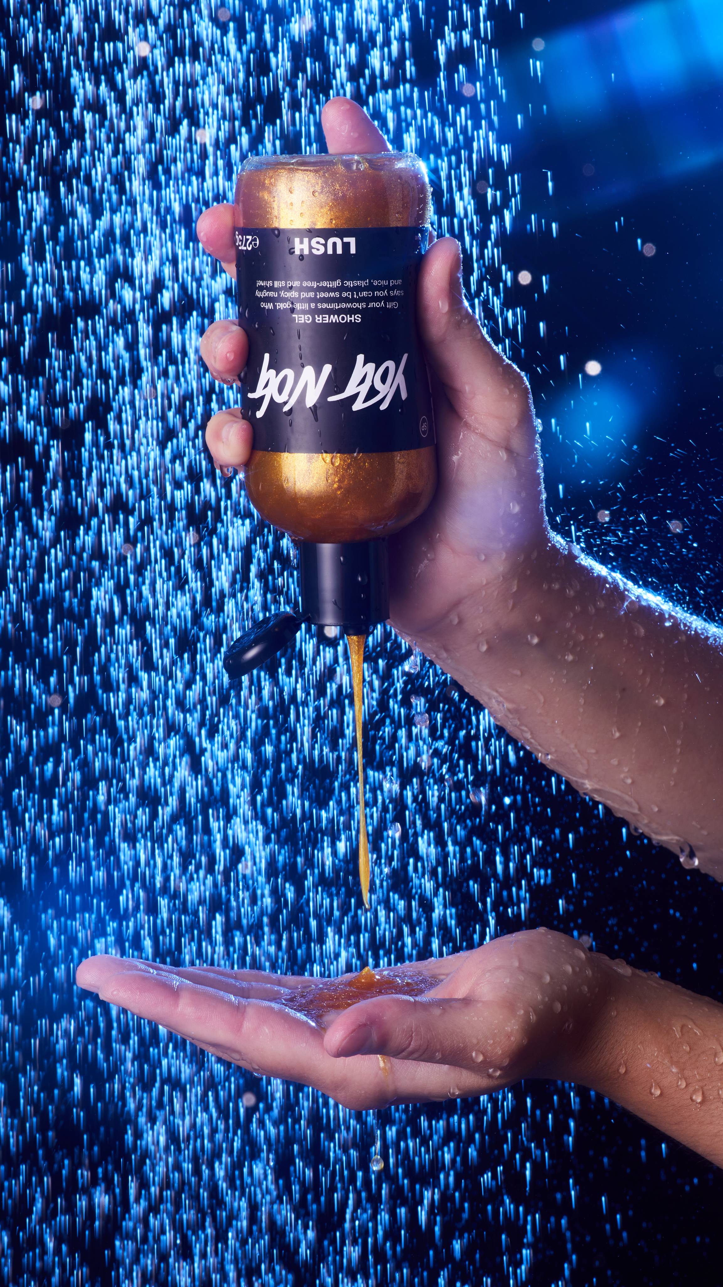 Image shows the model squeezing the bottle of Yog Nog shower gel into their hand under running shower water. 